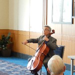 A man is seated and playing a cello